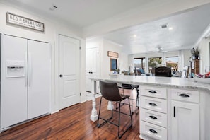A kitchen with white cabinetry, a marble countertop, and a bar stool.