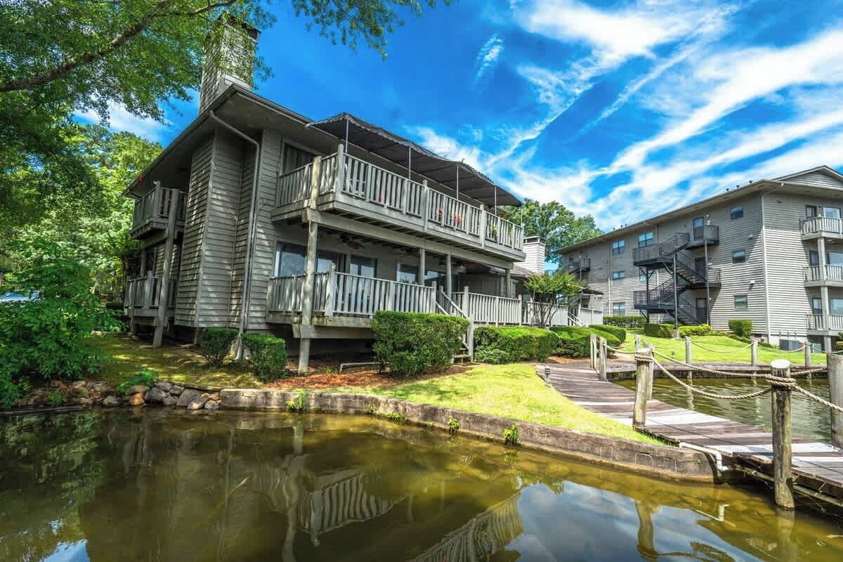 A two-story building with a balcony, a small pond, and a dock.