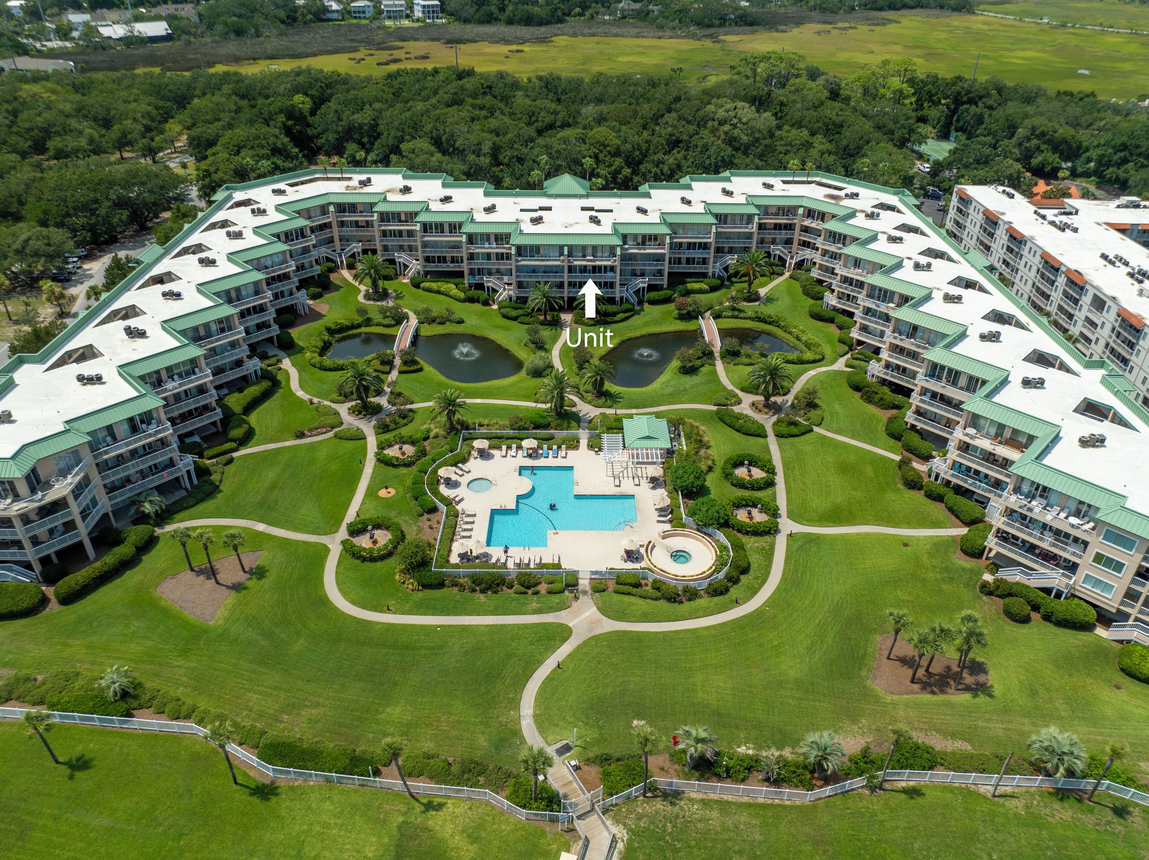 Un hotel moderno y espacioso con varias unidades, una piscina central y jardines ajardinados.