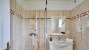 Un baño con ducha, lavamanos y espejo.