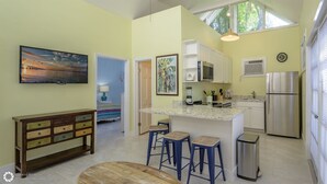 Una cocina moderna con una isla central, taburetes de bar, un refrigerador y un cuadro en la pared.