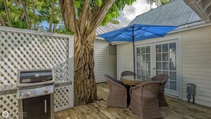 An outdoor patio with a grill, wicker chairs, and a blue umbrella. - Get your ISLAND STLYE on! (Key West)