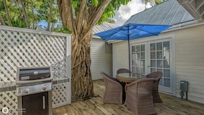 An outdoor patio with a grill, wicker chairs, and a blue umbrella. - Get your ISLAND STLYE on! (Key West)