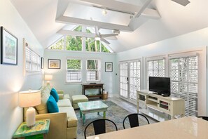 A bright living room with a high ceiling, large windows, a television, and a cozy seating area. - Get your ISLAND STLYE on! (Key West)