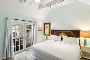 A bedroom with a bed, two bedside tables, a nightstand, a window with curtains, and a ceiling fan. - Get your ISLAND STLYE on! (Key West)