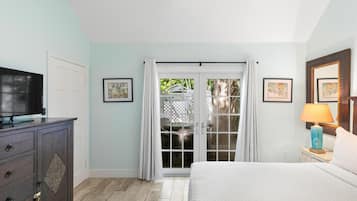 A bedroom with a bed, a television, a dresser, and a window with curtains.