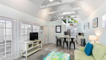 A compact living space with a television, seating area, kitchenette, and a ceiling fan.