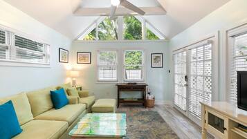 A cozy living room with a ceiling fan, a sofa, a coffee table, and a TV stand.