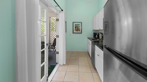 A kitchen with a stainless steel refrigerator, white cabinets, and a tiled floor.