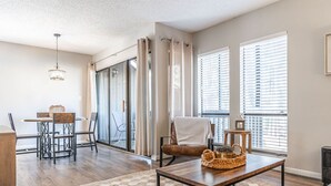 A spacious living room with a dining area, large windows, and a view of the city.