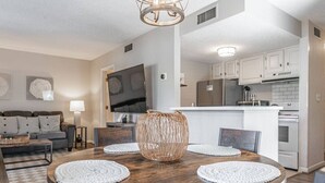 A dining area with a round wooden table, woven centerpiece, and white placemats.