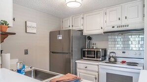 A modern kitchen with white cabinets, a stainless steel refrigerator, a microwave, and an oven.