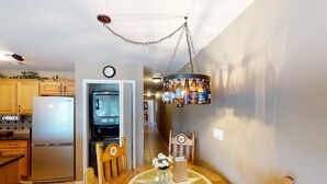A kitchen with wooden cabinets, a stainless steel refrigerator, a microwave, and a hanging light fixture. - Ww I303 Guadalupe Paradise! 3 Bedroom Condo by RedAwning (New Braunfels)