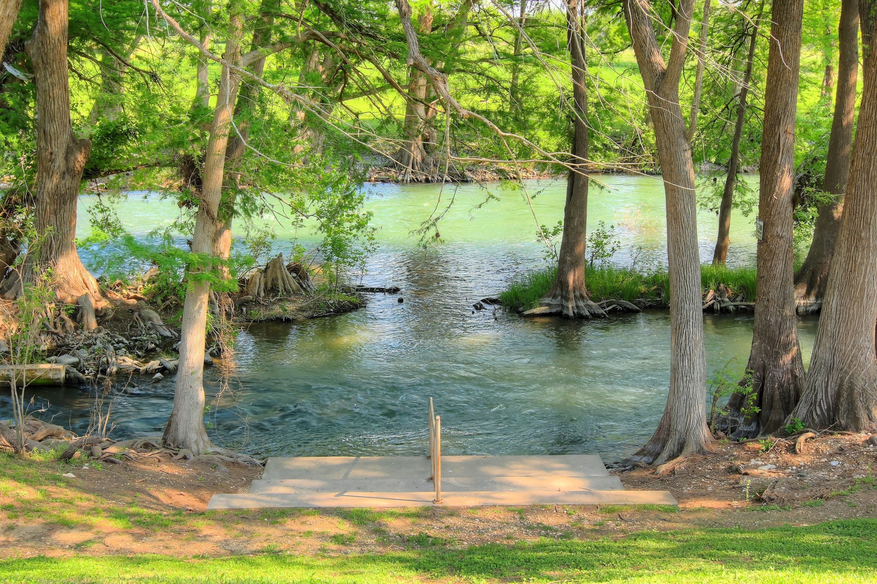 A serene riverside area with a concrete viewing platform and trees.