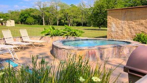 A backyard with a hot tub, lounge chairs, and a barbecue grill. - Ww I303 Guadalupe Paradise! 3 Bedroom Condo by RedAwning (New Braunfels)