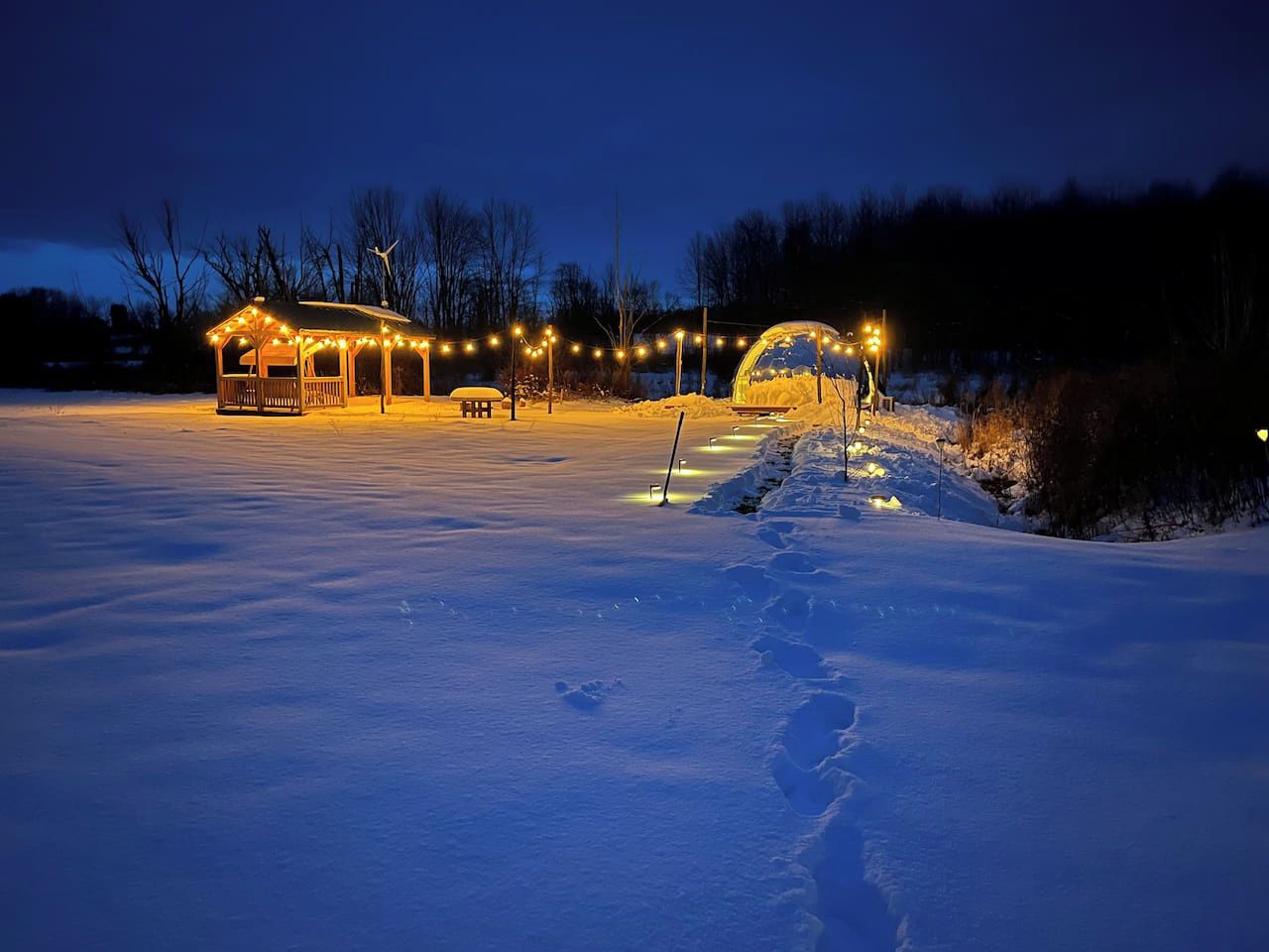 A snow-covered outdoor area with a gazebo and string lights.