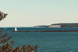 A lighthouse and pier extending into a body of water with a distant landmass. - Glamping Dome in Martville near Lake Ontario! (Martville)