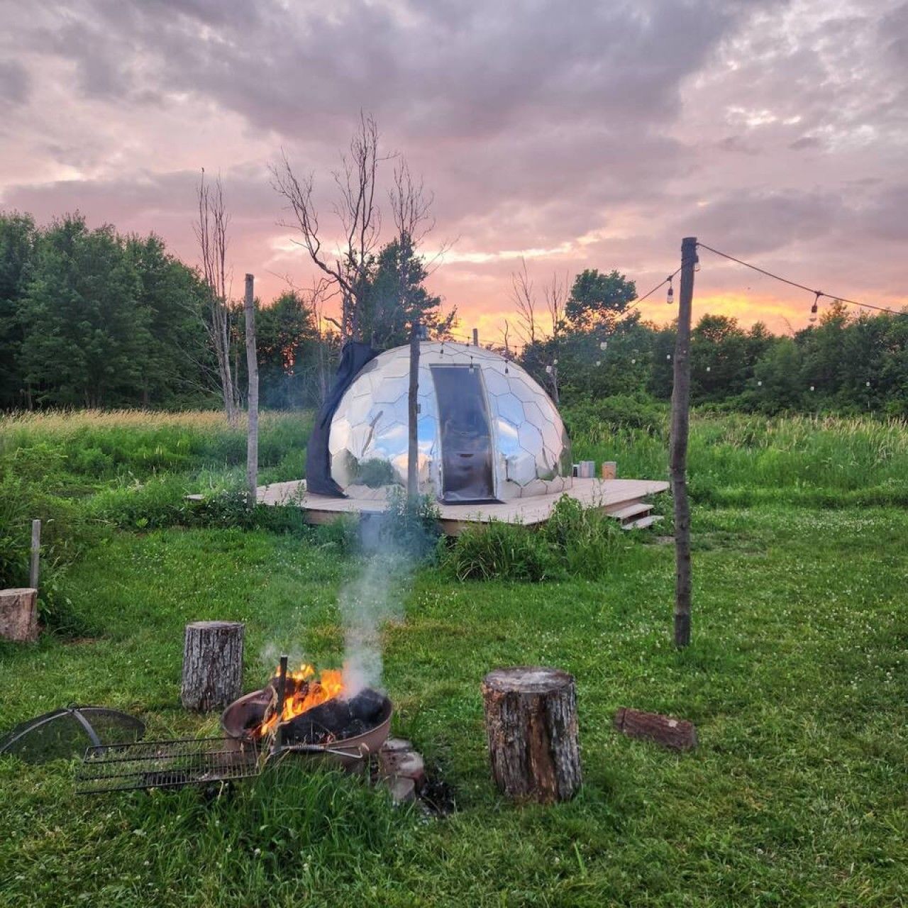 A geodesic dome structure with a fire pit in the foreground.
