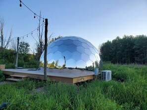 A geodesic dome structure with a wooden platform in a natural setting. - Glamping Dome in Martville near Lake Ontario! (Martville)