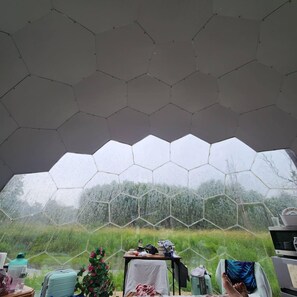 Een kamer met een zeshoekig plafond, een tafel met diverse voorwerpen, en uitzicht op groen buiten.