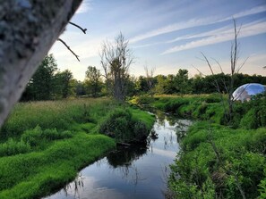 A natural landscape with a water body, vegetation, and a tent. - Glamping Dome in Martville near Lake Ontario! (Martville)