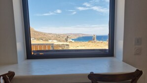 A room with a large window overlooking a coastal landscape. - MvibesMykonos homes and studios (Mykonos)