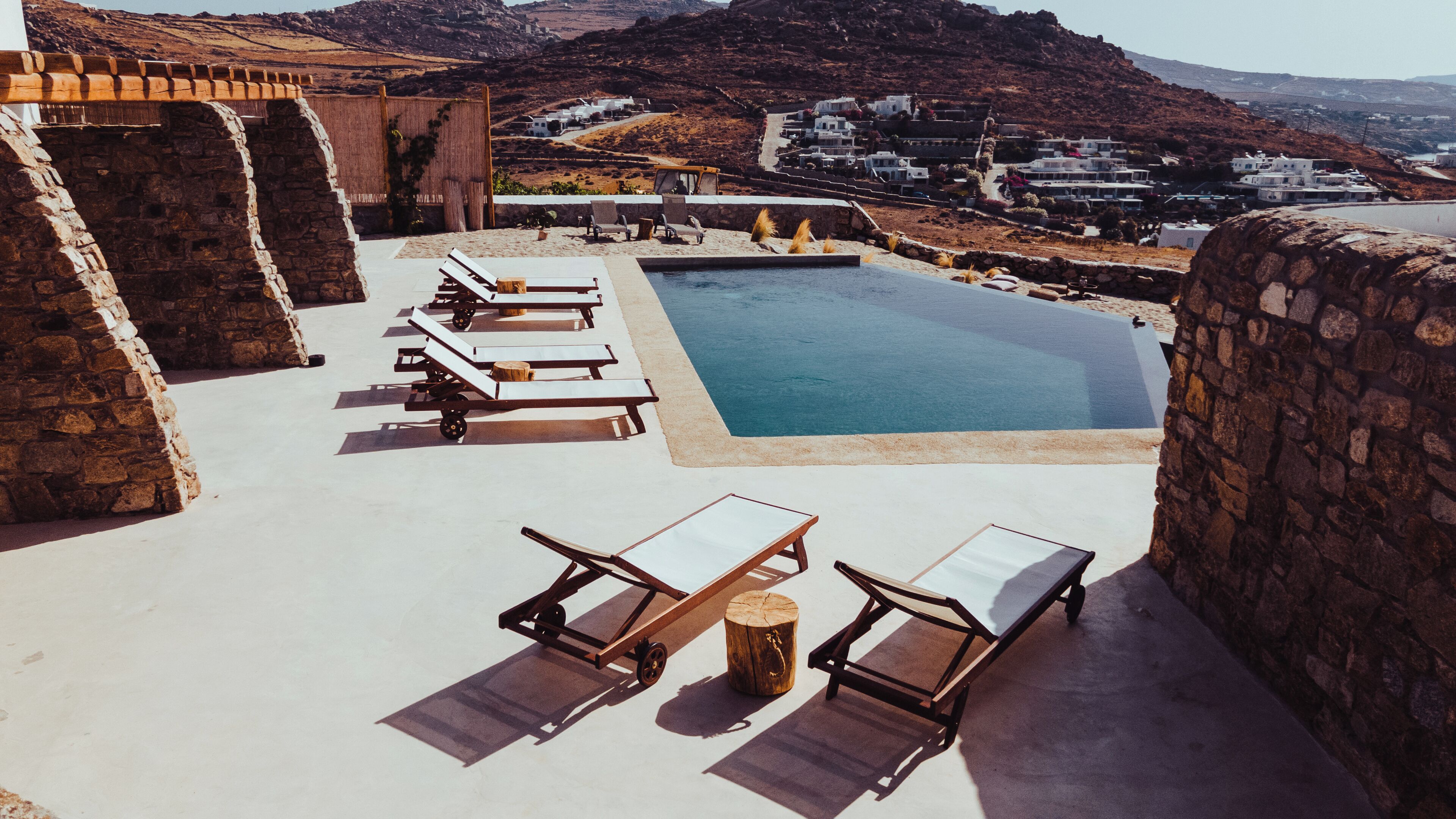 Un'area piscina con lettini e un muro in pietra.