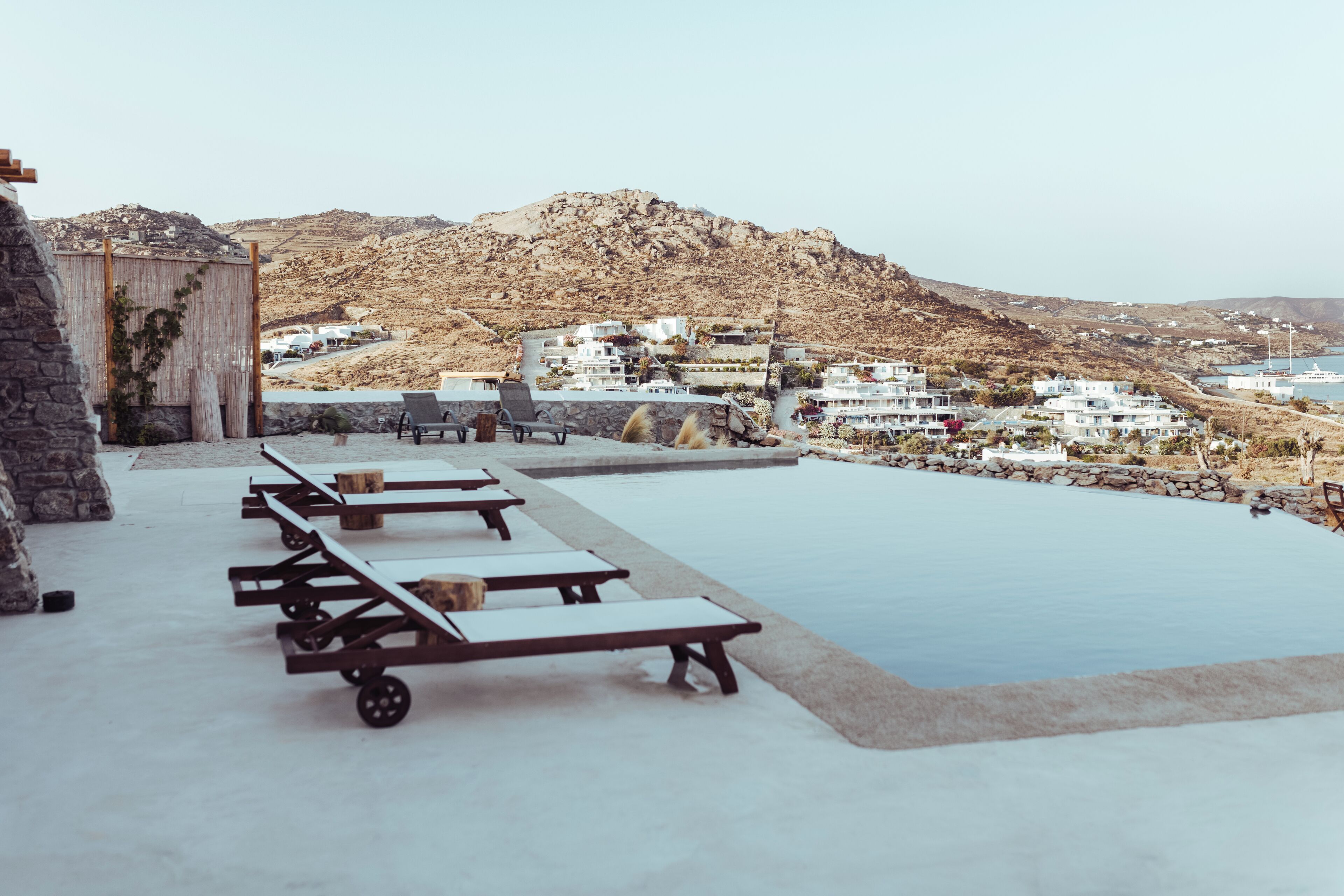 An infinity pool with lounge chairs and a stone building.