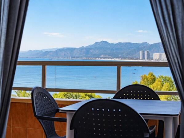 Un balcón con vista al mar y a las montañas, con dos sillas y una mesa.