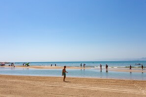 A beach with people walking and playing in the water. - Florazar II Sea Front Apartment Cullera (Cullera)