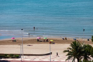 Uma praia com guarda-sóis, pessoas e um barco.