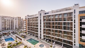 Un hotel moderno de varios pisos con piscina en la azotea y zonas de estar al aire libre.