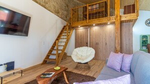 A loft-style living room with a wooden staircase, a white egg chair, a grey sofa, and a flat-screen TV mounted on the wall. - Casa S o Jos in Carvalhal (Bombarral)