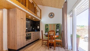 A modern kitchen with wooden cabinets, a dining area with a table and chairs, and a large window offering a view of the outdoors. - Casa S o Jos in Carvalhal (Bombarral)
