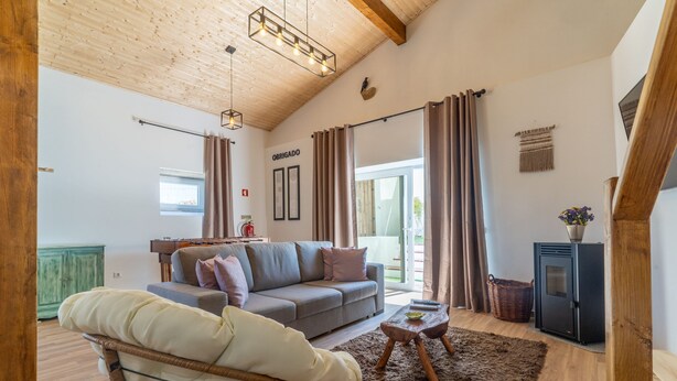 A cozy living room with a sofa, chair, wooden ceiling, and a small table. - Casa S o Jos in Carvalhal (Bombarral)