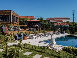 A pool area with a Buddha statue, outdoor seating, and a restaurant with a tiled roof.