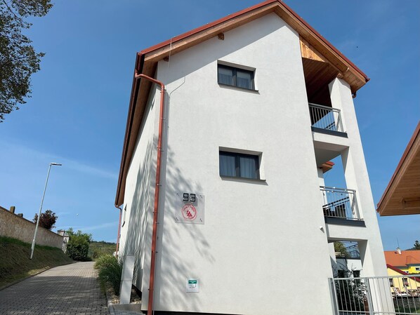 A multi-story building with a white facade, a balcony on the upper floor, and a visible number '93' on the side. - Stará vinice (Velke Zernoseky)