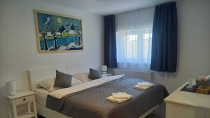 A neatly arranged bedroom with a bed, bedside tables, a painting, and a window with curtains. - Stará vinice (Velke Zernoseky)