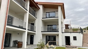A multi-story building with balconies, a stone fountain, and a grassy courtyard. - Stará vinice (Velke Zernoseky)