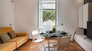 A modern kitchen with a dining table set for four, a sofa, and a TV. - Vernazzola Family Apartment (Genoa)