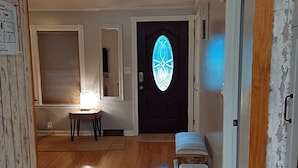 A hallway with wooden flooring, a door with a stained glass window, and a small table with a lamp. - RANCH WITH CACTUSES  Weekly/Monthly UP TO 50% OFF (Millsboro)