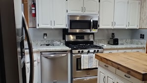 A modern kitchen with white cabinets, stainless steel appliances, and a wooden countertop. - RANCH WITH CACTUSES  Weekly/Monthly UP TO 50% OFF (Millsboro)