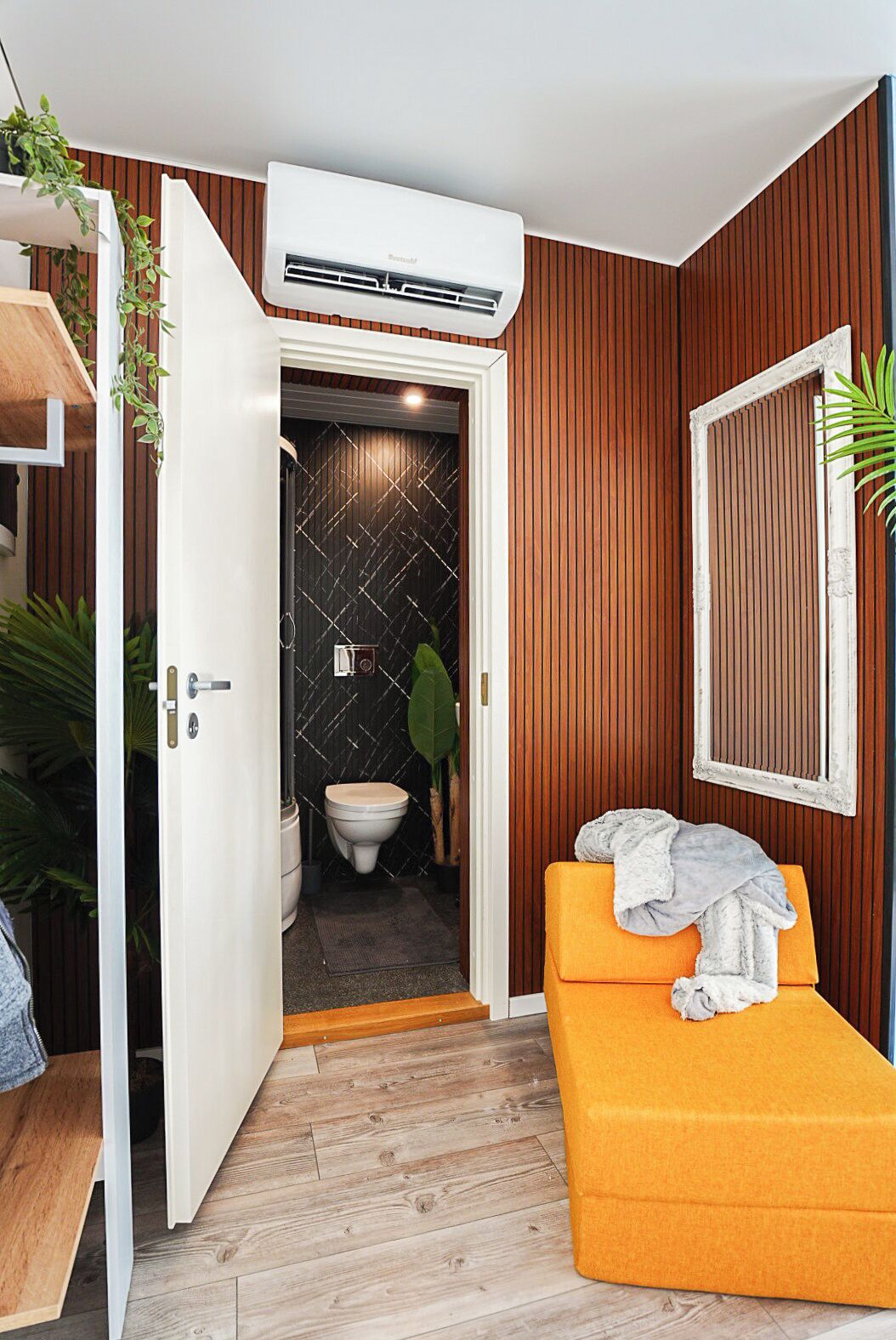A compact bathroom with a toilet, a shower area, and a small seating area with a towel.
