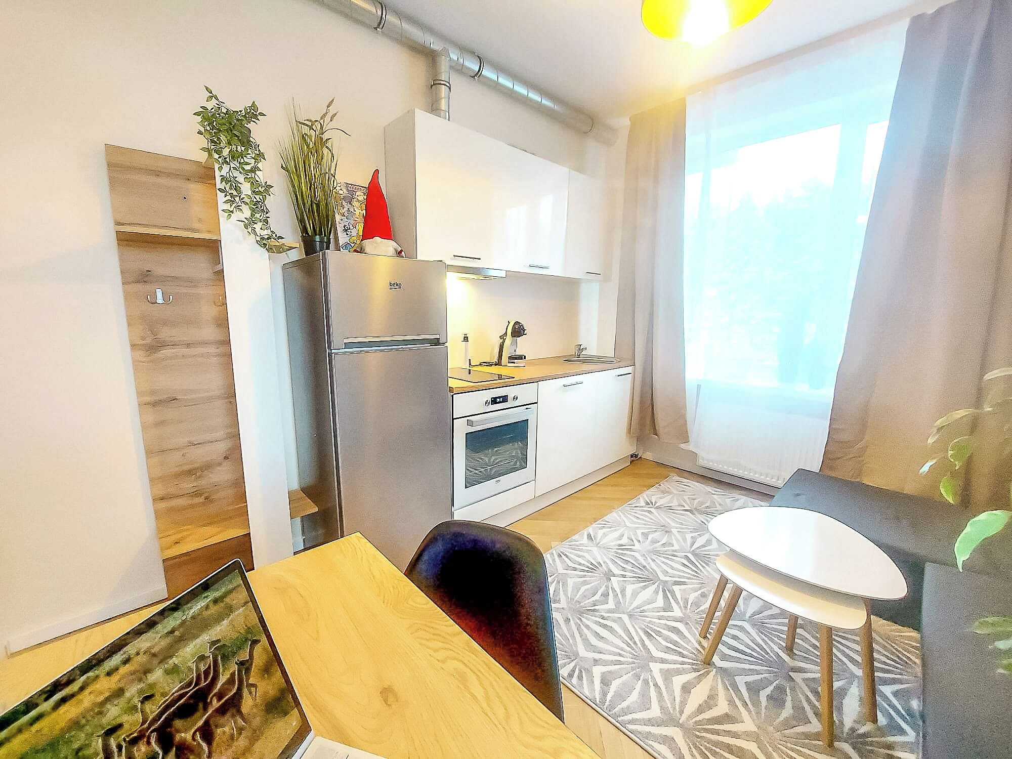 Cocina compacta con refrigerador, horno y pileta. Hay una mesa de comedor con una silla y un tapete pequeño.