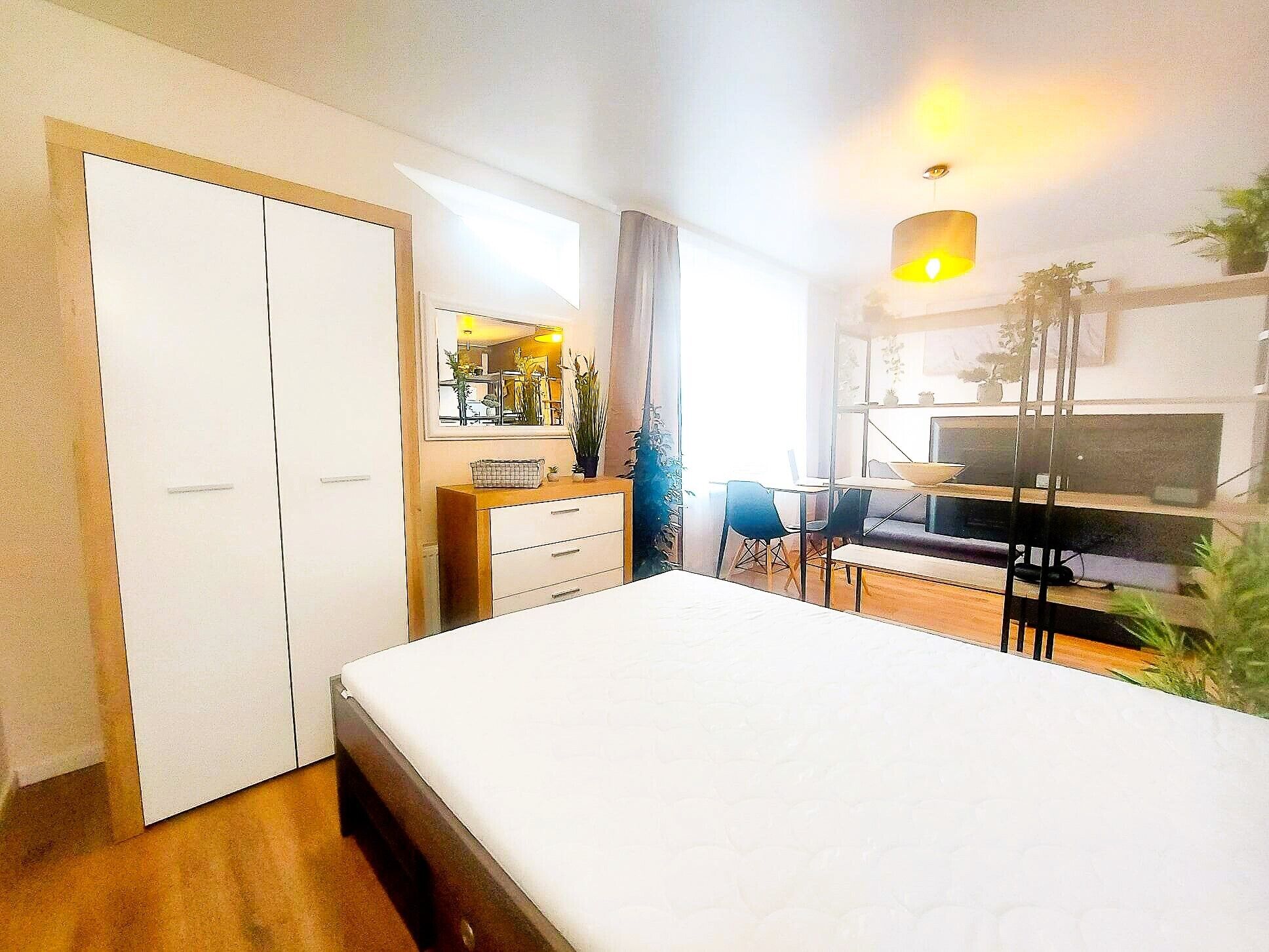 Un dormitorio con cama, escritorio, silla, cómoda y televisor.