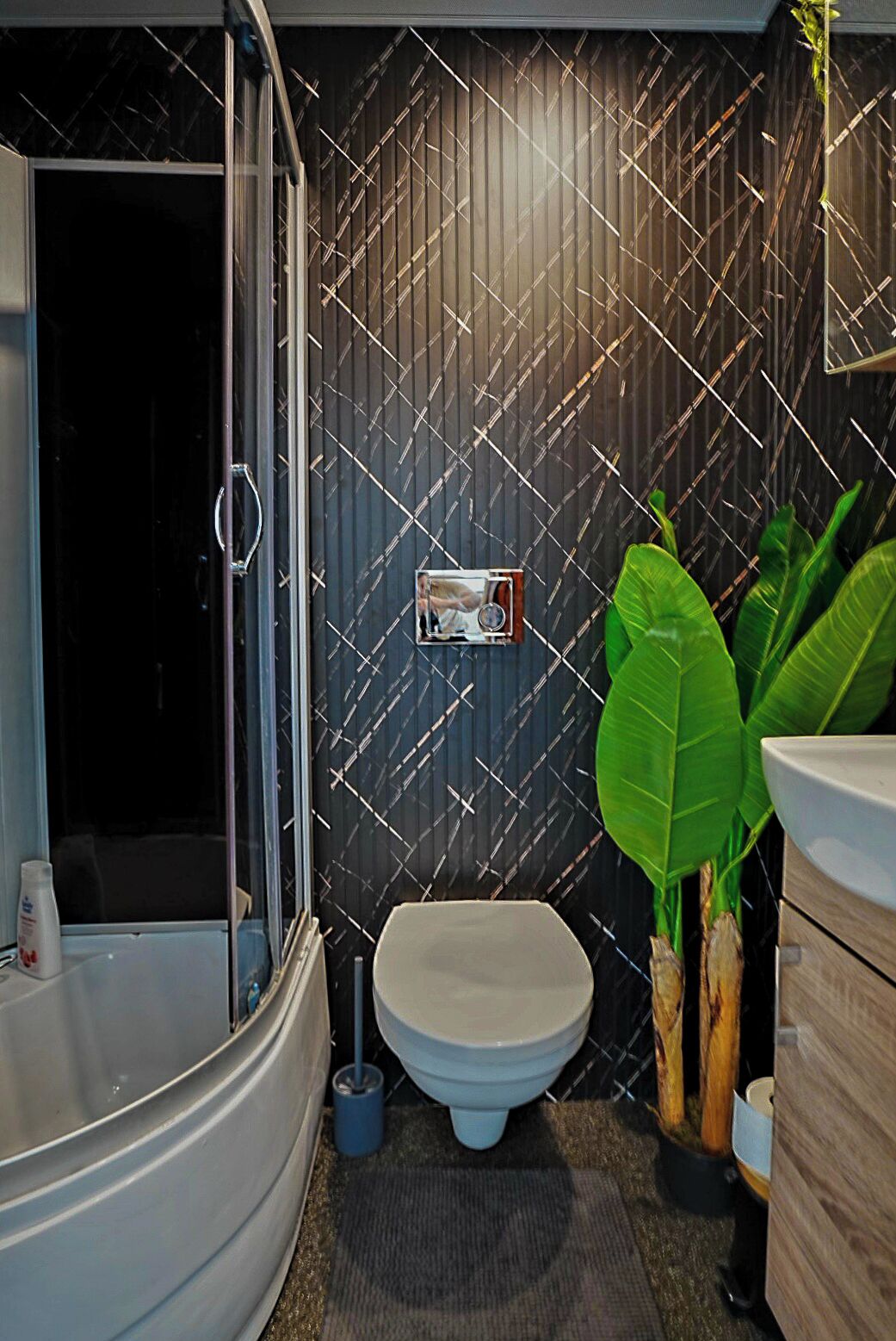 Et moderne badeværelse med en glasafskærmet brusekabine, toilet og håndvask.