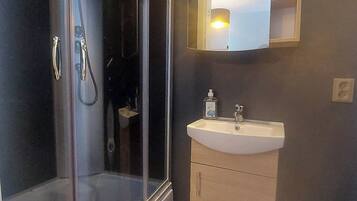 Un baño moderno con cabina de ducha de vidrio, un lavabo y un espejo.