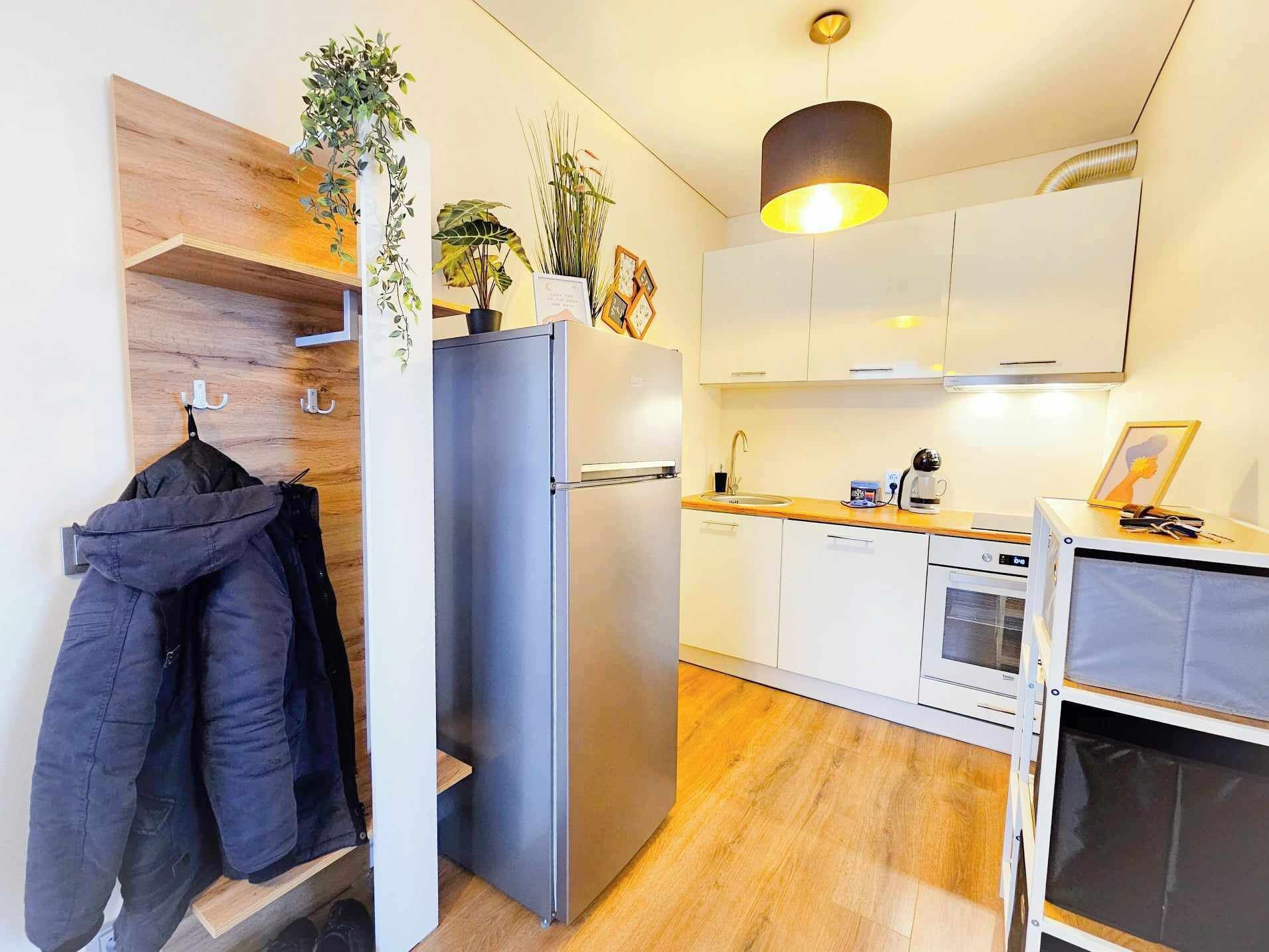 Una cocina compacta con refrigerador, lavamanos y un pequeño comedor.