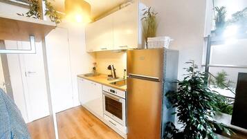 Una cocina compacta con horno integrado, un refrigerador y un lavamanos.