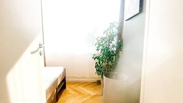 Un pasillo estrecho con suelo de madera, una planta en maceta y una puerta con manija.